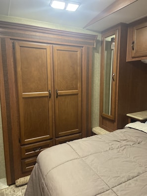 Ein Schlafzimmer mit großem Kleiderschrank, einem Bett und einem Spiegel.