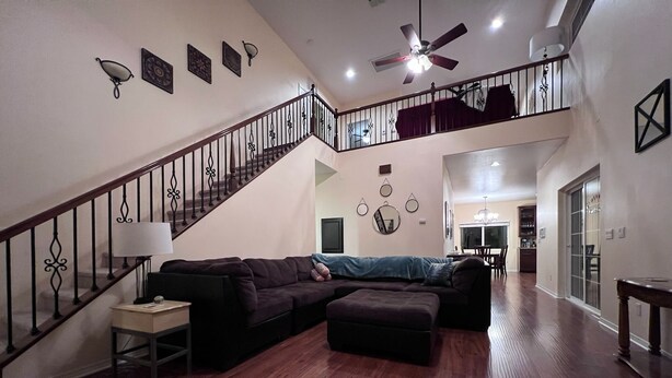 A spacious living room with a large sectional sofa, a small table, and a staircase leading to an upper level. - Mountain Escape: Sleeps Multiple Families with Pool Table & Game Room (Running Springs)
