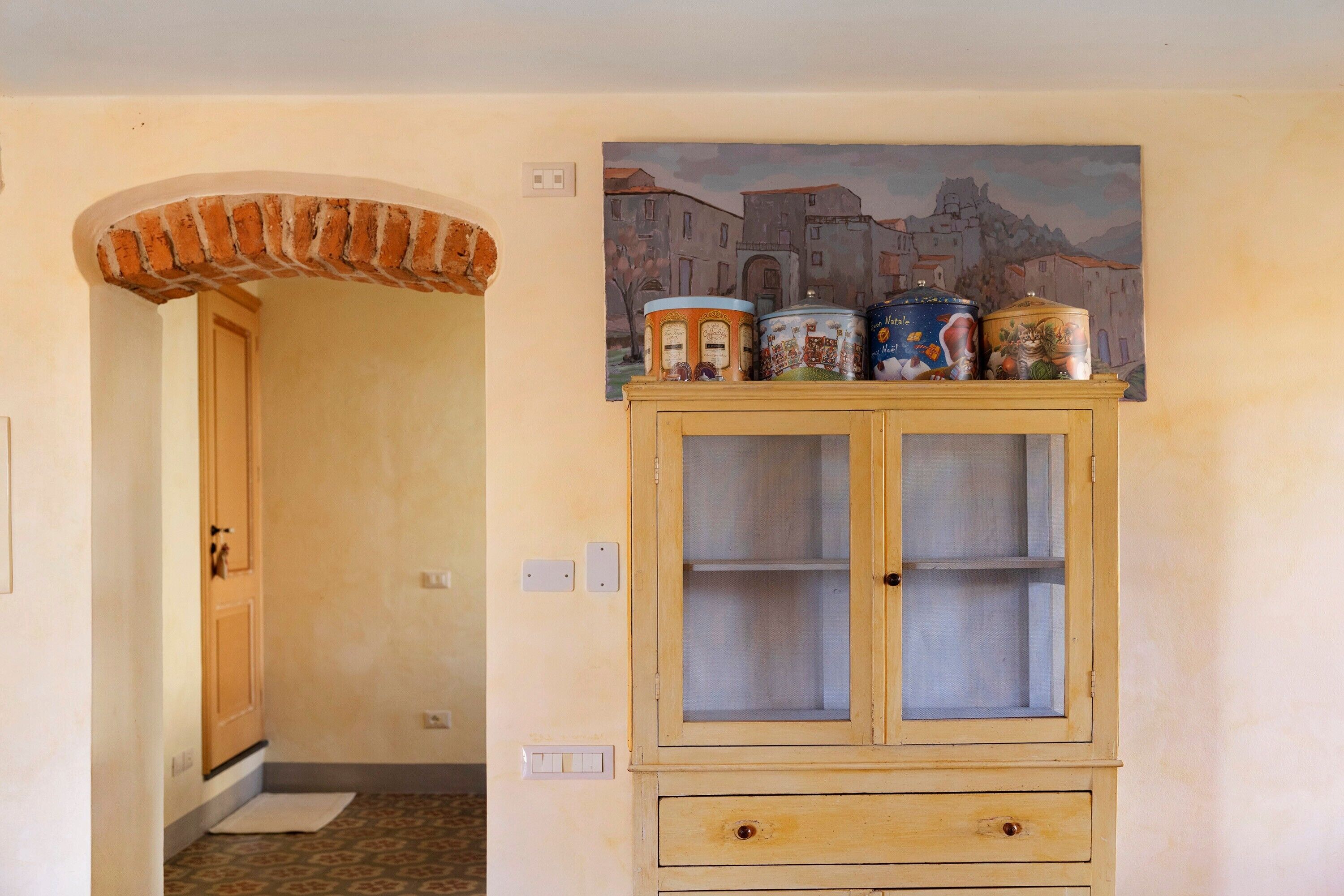 Une pièce avec un meuble en bois, une porte et un tableau accroché au mur.