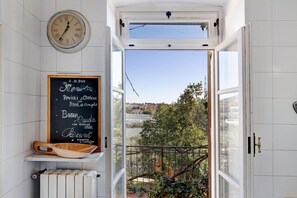 A kitchen with a chalkboard menu, a wooden bowl, and a view of a balcony with greenery. - Apartment "Residenza Stoechas White" with Wi-Fi, Garden & Terrace (Albenga)