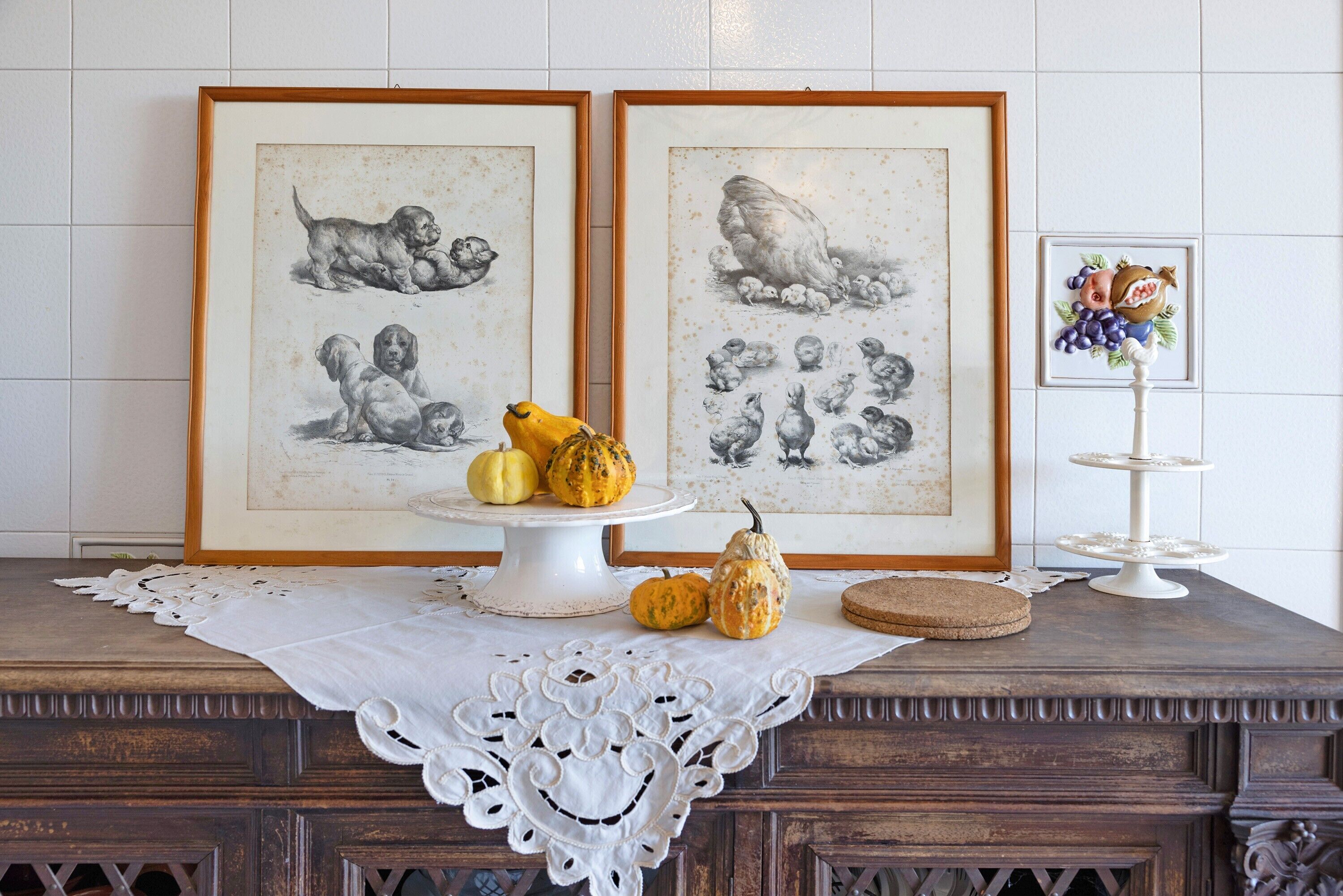 Una mesa de madera con mantel de encaje blanco, un soporte para pastel blanco y un marco con una foto de cachorros.