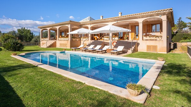Une grande maison dotée d’une piscine, d’un espace extérieur aménagé pour se détendre et d’un patio couvert.