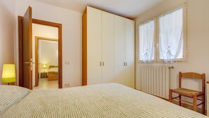 A bedroom with a bed, wardrobe, chair, and a window with curtains. - Apartment 'Succu La Taggiasca' with Mountain View & Terrace (Stellanello)