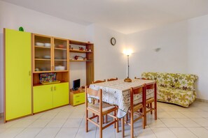 Un comedor con una mesa, sillas, un sofá y un armario con estantes.