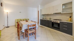 A kitchen with a dining table, chairs, cabinets, a stove, and a floor lamp. - Apartment 'Succu La Taggiasca' with Mountain View & Terrace (Stellanello)