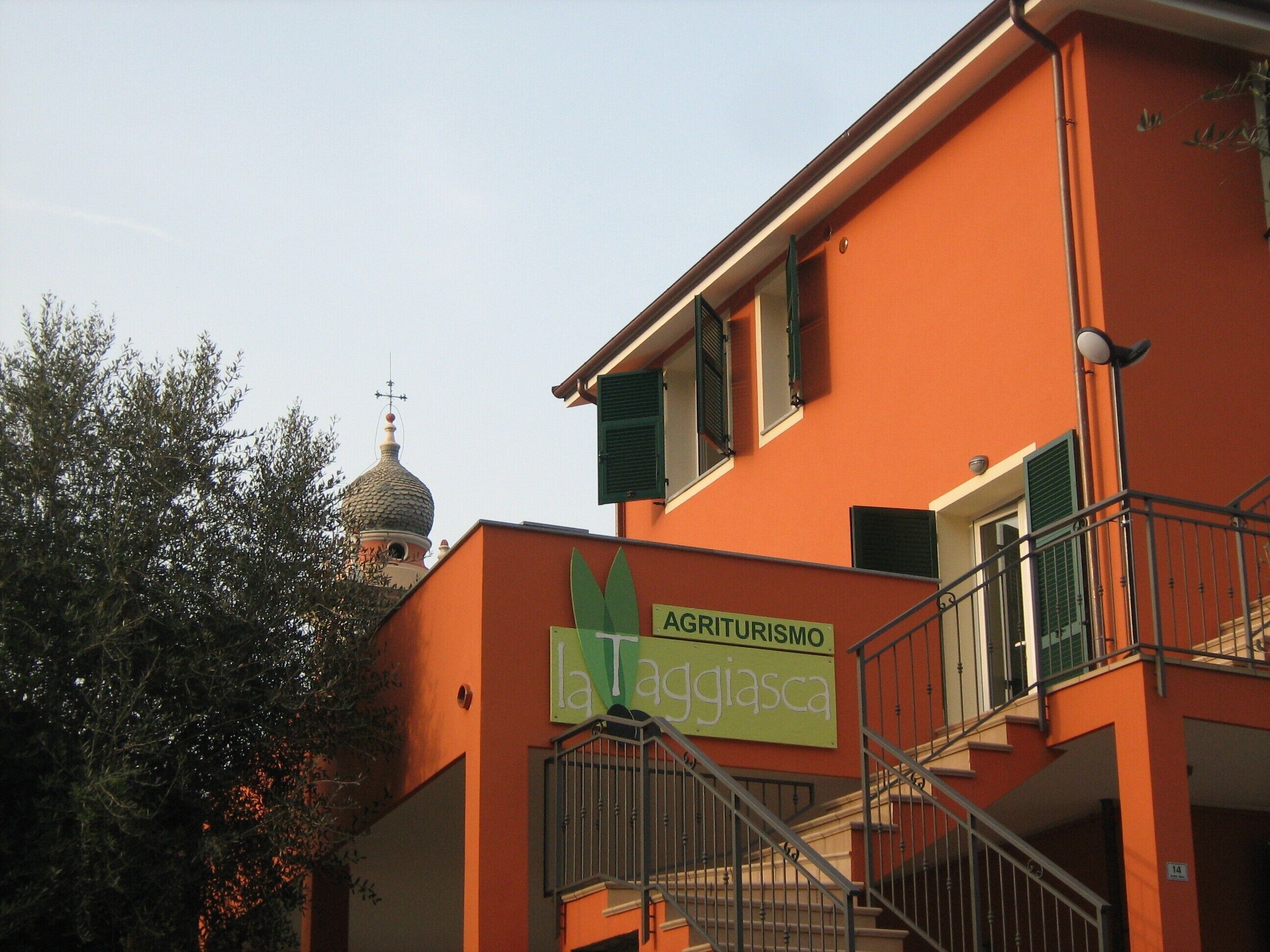 A building with a sign reading 'Agriturismo La Tagliacqua' and a staircase leading to an upper level.