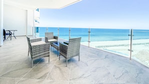 A balcony with wicker furniture and a view of the ocean.