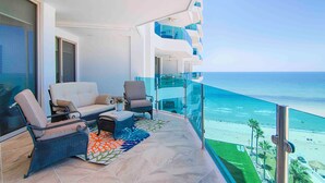 A balcony with a view of the ocean, furnished with a sofa, chairs, and a small table. - Hotel Esmeralda Beach Resort (Puerto Peñasco)