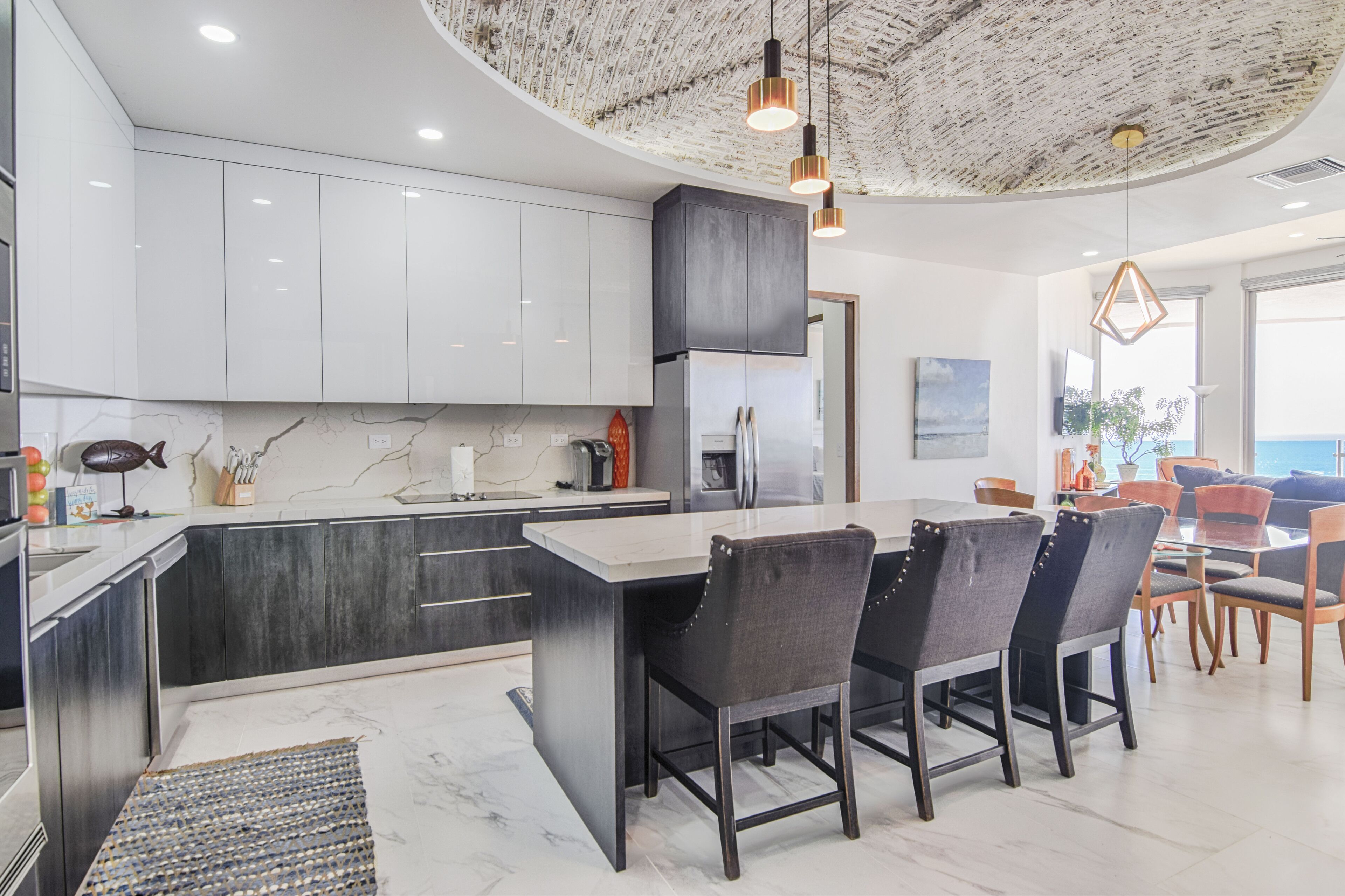 Une cuisine moderne avec des meubles blancs, un îlot central et un coin repas comprenant des chaises et une table.