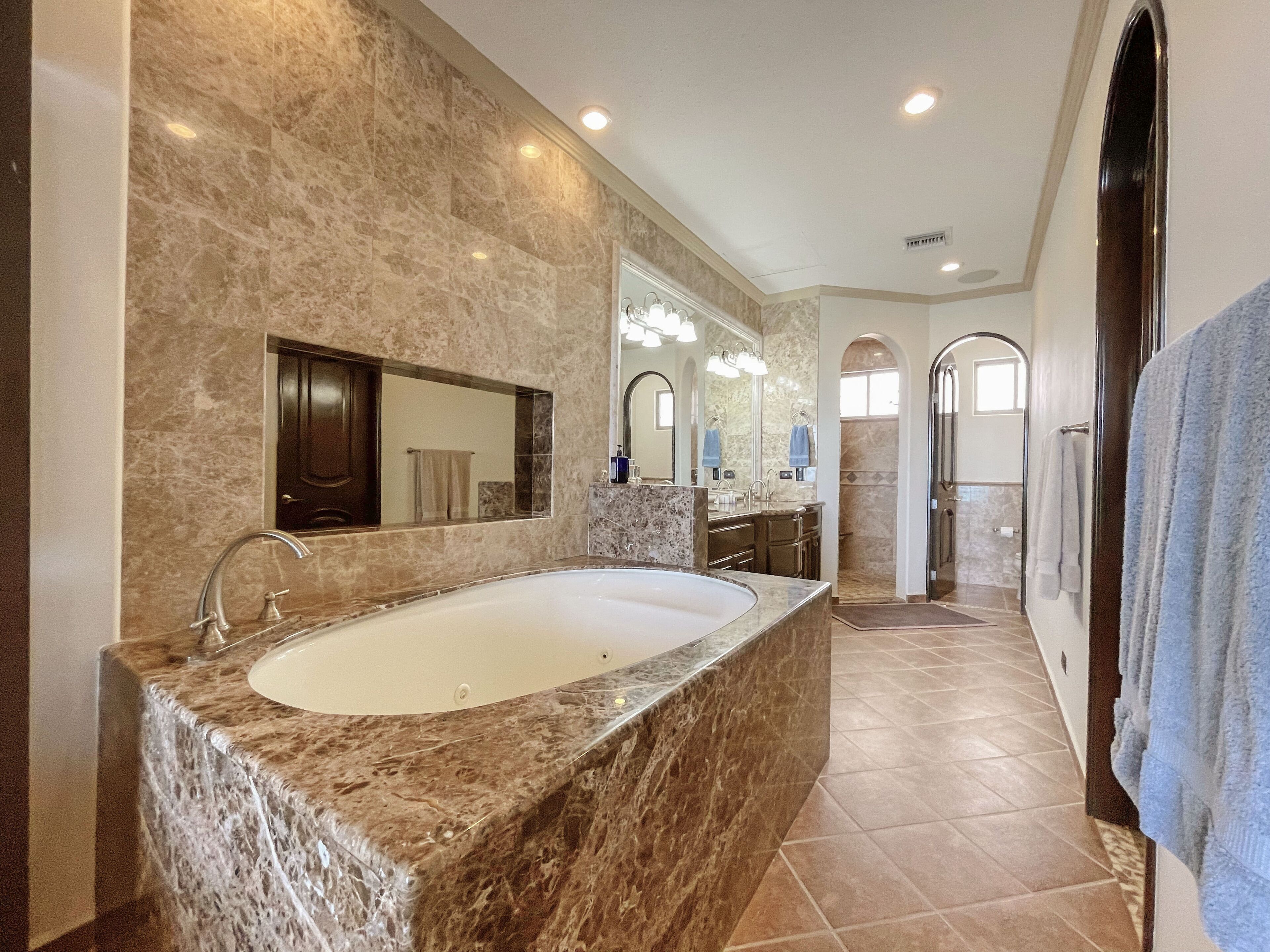 A spacious bathroom with a large marble sink, a walk-in shower, and a separate vanity area.