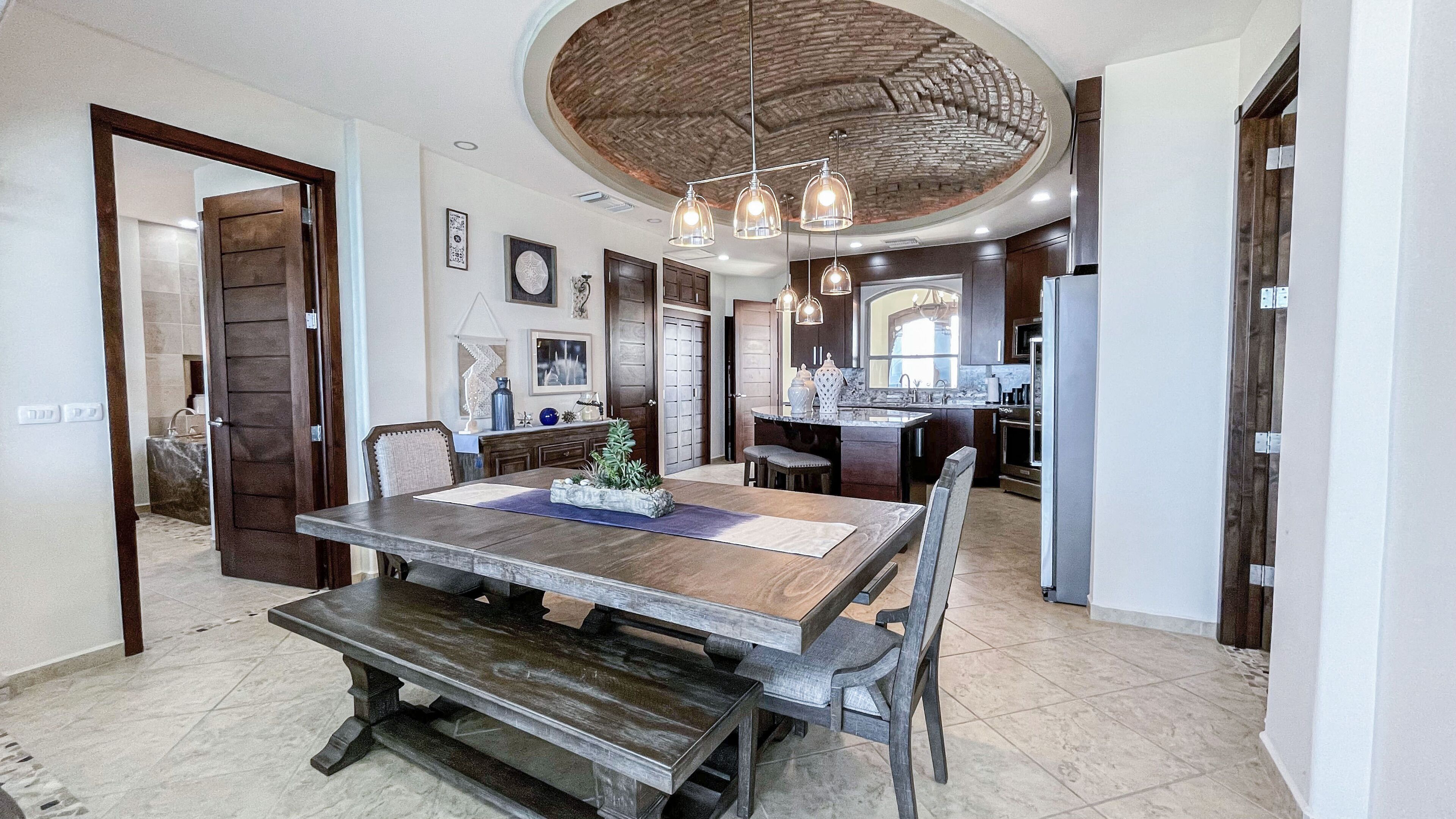 Un comedor amplio con una gran mesa de madera, sillas oscuras y un techo rústico.