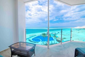 A balcony with a glass table and chairs, overlooking a pool area and beach. - Hotel Esmeralda Beach Resort (Puerto Peñasco)