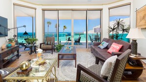 A spacious living room with a large glass door leading to a balcony with a view of the ocean. - Hotel Esmeralda Beach Resort (Puerto Peñasco)