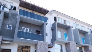 A multi-story residential building with balconies, large windows, and a brick facade.
