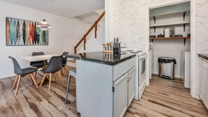 Uma cozinha moderna com ilha central, piso de madeira e prateleiras embutidas.
