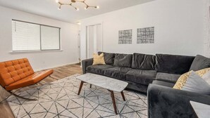 Uma sala de estar moderna com um sofá de couro, uma mesa de centro de madeira e um tapete com padrão geométrico.