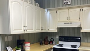 Eine Küche mit weißen Schränken, einem Herd und einer Kaffeemaschine.