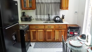 A compact kitchen with wooden cabinets, a black refrigerator, a microwave, and a gas stove. - Serenity's Condo 2 Bedroom Apartment (Montego Bay)