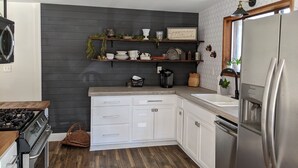 A modern kitchen with white cabinets, a stainless steel refrigerator, and a wooden countertop. - Rustic modern cabin surrounded by trees and large yard 25 miles from Waco/Temple (Lott)