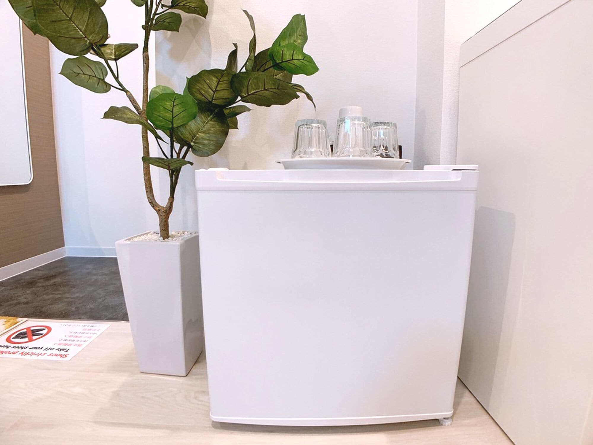 A white cabinet with a potted plant beside it.