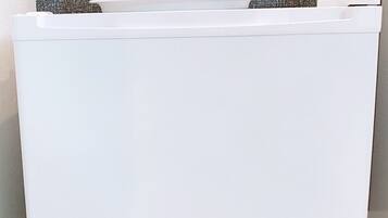 A white storage unit with a flat surface and a handle, containing several clear glasses and a white object.