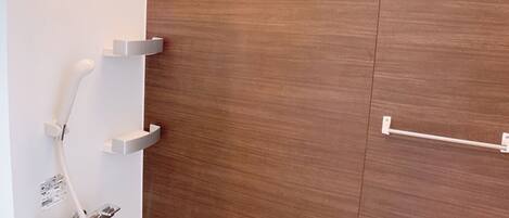 Un baño moderno con tocador de madera, inodoro empotrado y zona de ducha con cabezal de ducha manual.