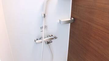 A bathroom with a shower, a toilet, and a wooden door.