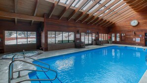 An indoor swimming pool with wooden beams and large windows.