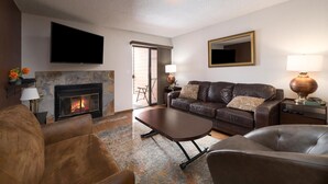 A living room with a fireplace, leather sofa, and a flat-screen TV.
