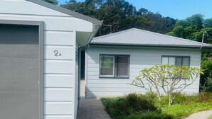 Un immeuble résidentiel moderne à deux étages, doté d’un garage, d’une pelouse bien entretenue et surplombant un ciel dégagé.