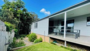 Une maison moderne dotée d’un patio couvert, d’un petit jardin et d’une clôture en bois.
