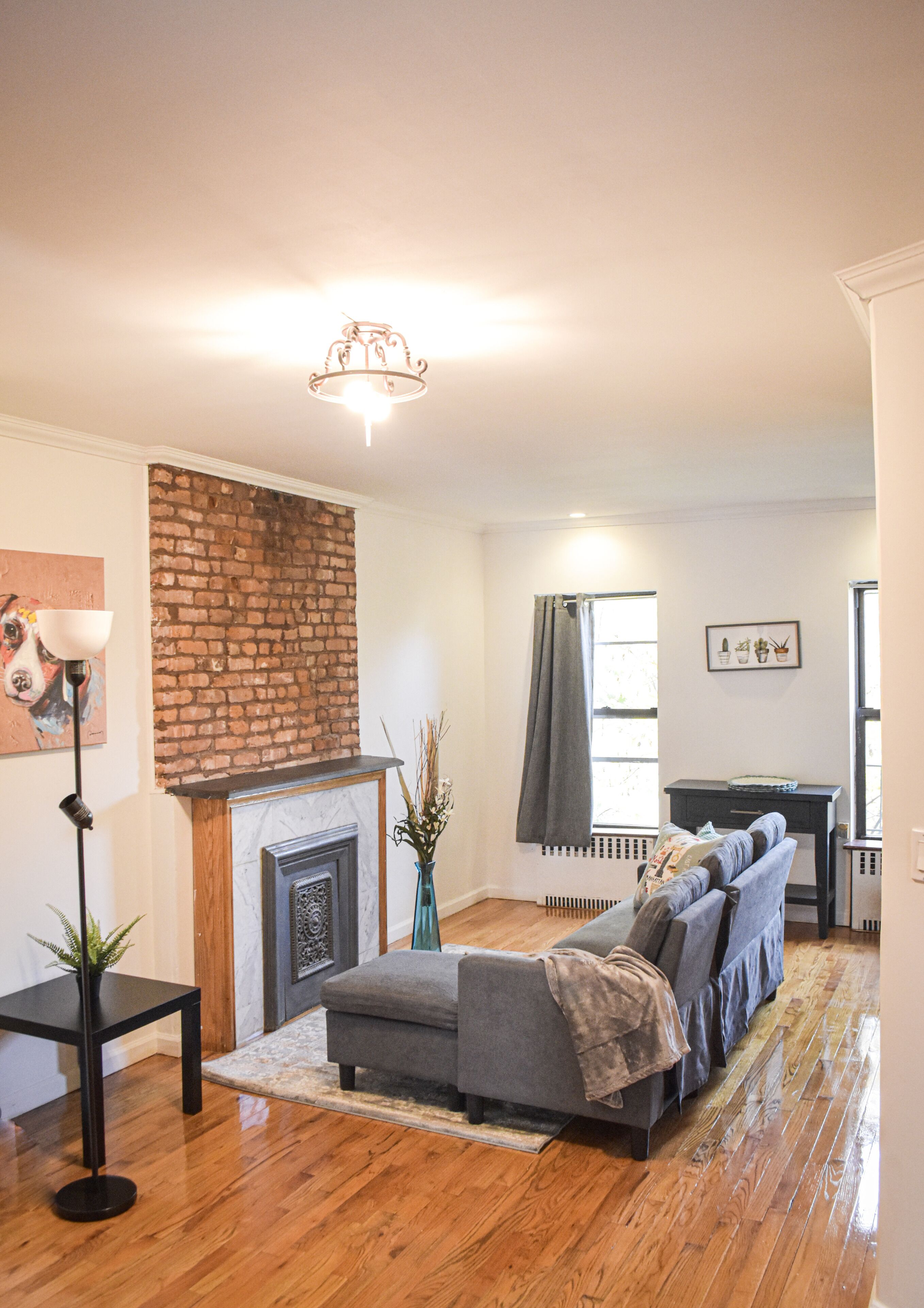 A living room with a fireplace, a sofa, a lamp, and a brick accent wall.