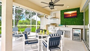 A modern kitchen with a built-in grill, a dining area with striped chairs, and a large window overlooking a green landscape. - LUXURY Villa ALEXA Naples

Modern Voice controlled Villa with SALT WATER POOL (Naples)