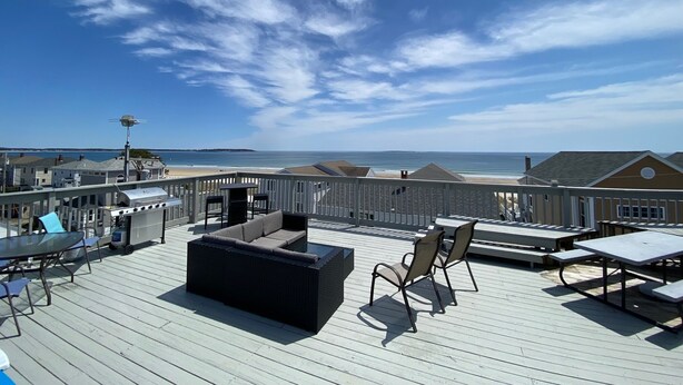 Terraza en la azotea con mobiliario exterior, una parrilla y vistas a la playa y al océano.