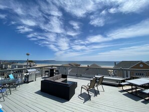 Une terrasse sur le toit avec des sièges d’extérieur, un barbecue et une vue sur la plage et l’océan.