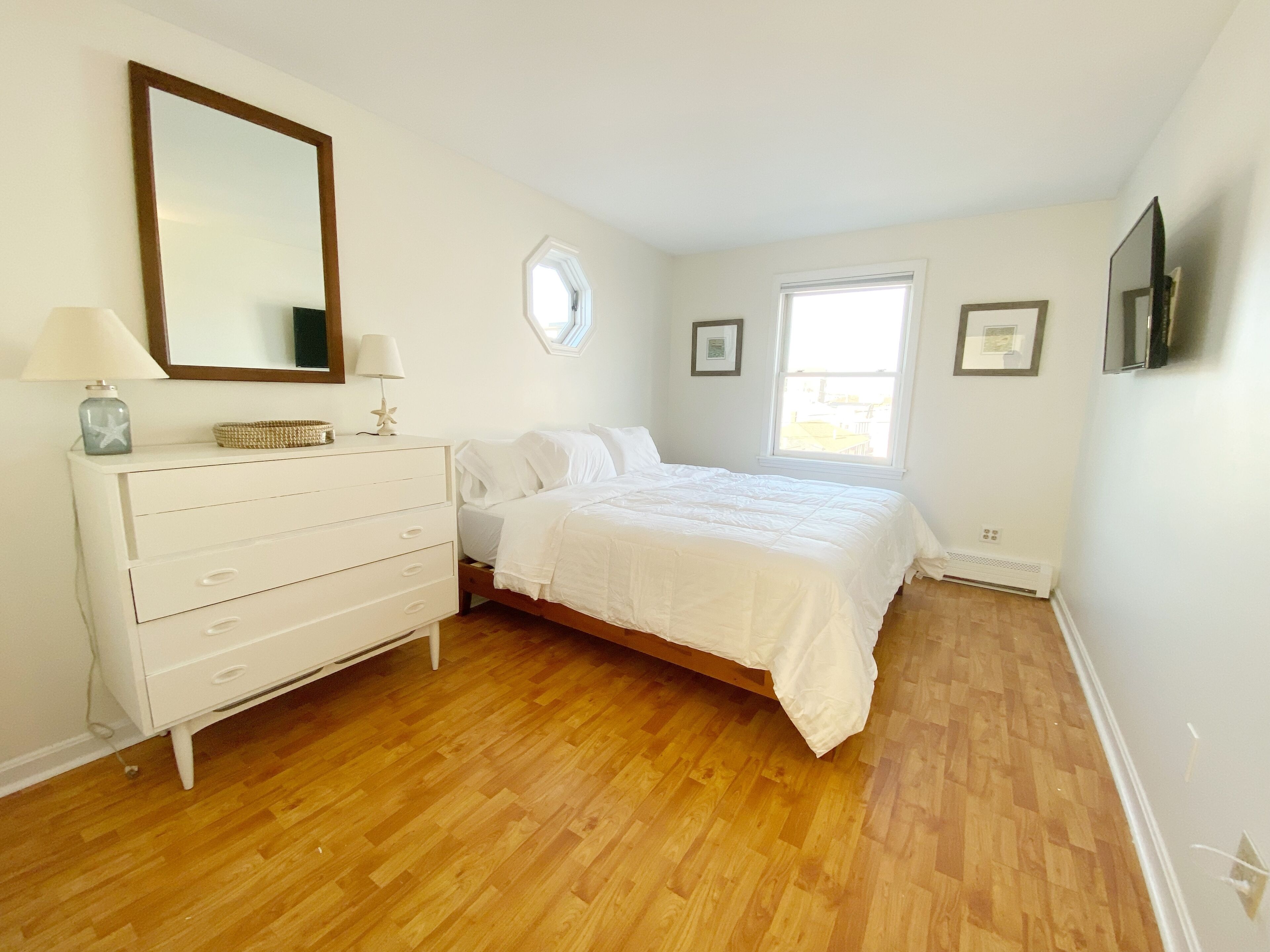 Une chambre à coucher avec un lit, une commode et un grand miroir.