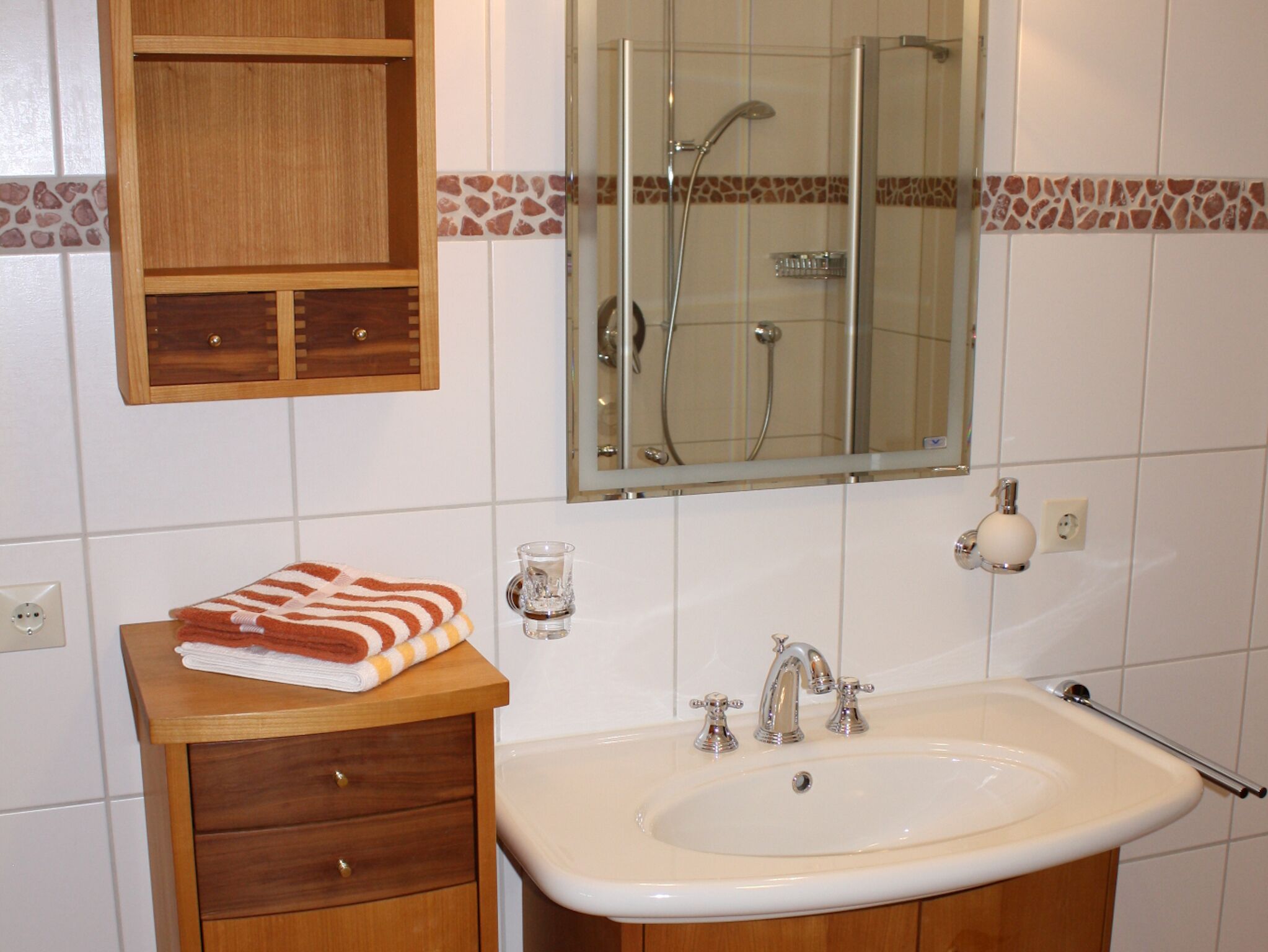 Een badkamer met een houten wastafel, een wasbak en een douche.