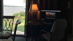 A room with a desk, a chair, a lamp, and a television displaying a scenic view. - NEW-Waterfront Lodge-Private dock/slip, Kayak, swim, fish, water view from deck (Grove)