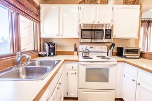 A kitchen with white cabinets, a stainless steel sink, a stove, a microwave, and a toaster. - Sunrise 9 (Mammoth Lakes)