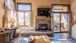 A cozy living room with a stone fireplace, a flat-screen TV, and a comfortable sofa.
