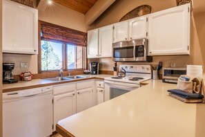 A kitchen with white cabinets, stainless steel appliances, and a wooden countertop. - Sunrise 9 (Mammoth Lakes)