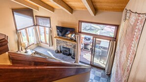 A staircase leading to a living area with a fireplace, a television, and large windows.