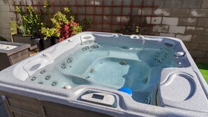 A hot tub with a control panel, surrounded by potted plants and a brick wall. - NORTH HOLLYWOOD GEM: 2BR HOME w/ PRIVATE HOT TUB, PATIO/YARD & EV CHARGER p42 (Los Angeles)
