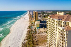 A coastal hotel with a beach view, a pier, and a high-rise building.