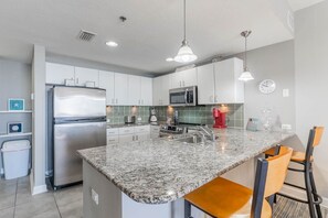 A modern kitchen with granite countertops, stainless steel appliances, and a central island with bar stools.