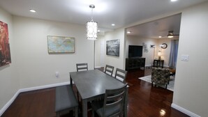 A dining area with a dark wooden table and chairs, a world map on the wall, and a modern chandelier. - 3B/2Bth + Dinning in Historical Tower District (Fresno)