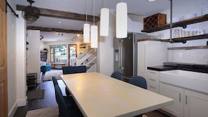 A modern kitchen with a dining area, built-in shelves, and a staircase leading to a balcony. - Eagle's Nest, hot tub, great views (Mt. Crested Butte)