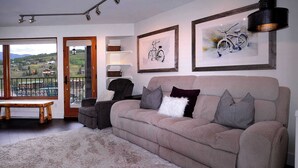 A living room with a sofa, a chair, a table, and a view through a door. - Eagle's Nest, hot tub, great views (Mt. Crested Butte)