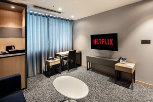 Una habitación de hotel moderna con escritorio, silla y televisor que muestra el logotipo de Netflix.