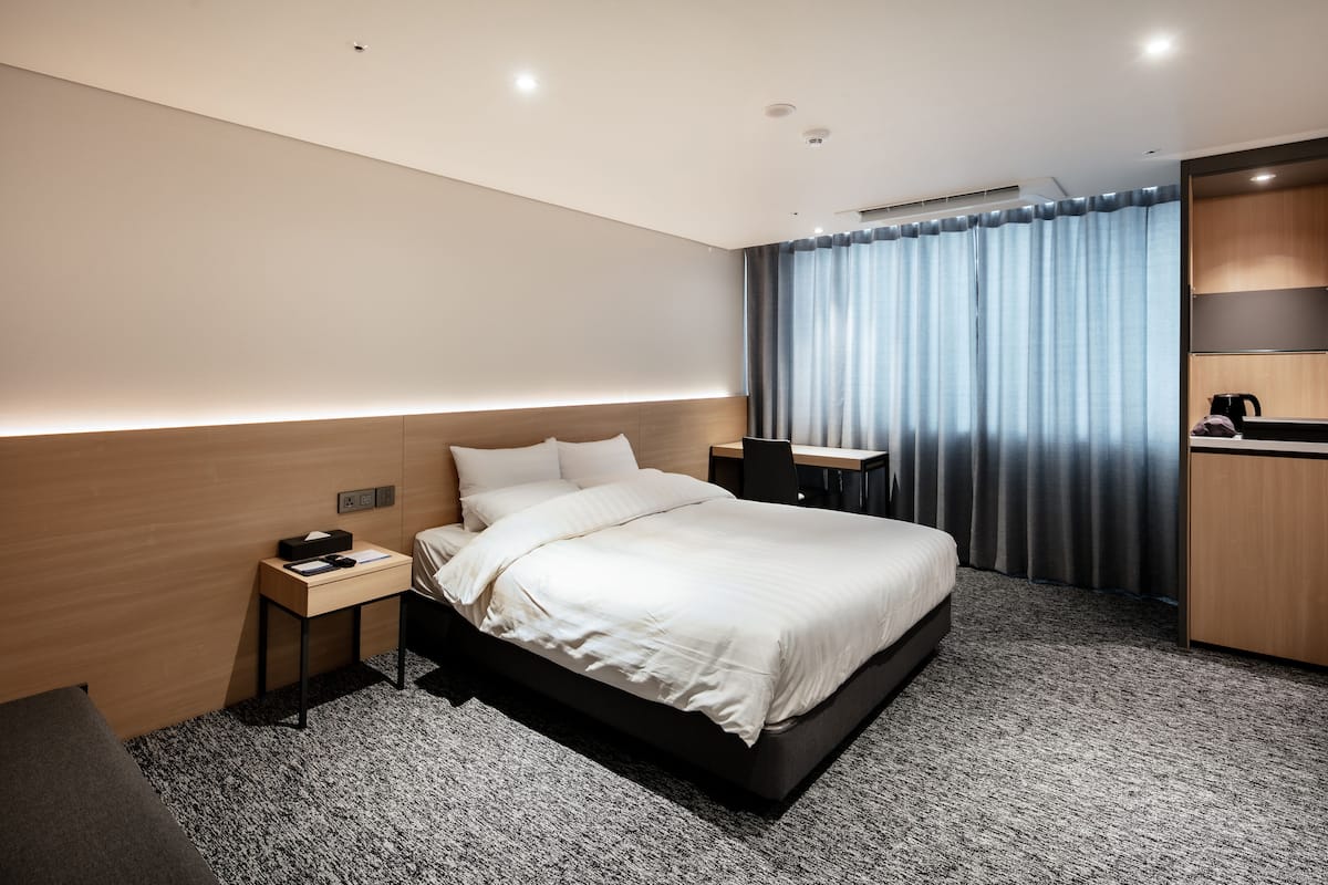 Una habitación de hotel moderna con una cama grande, un escritorio y un armario.